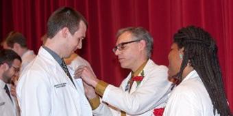 person pinning someone's white coat